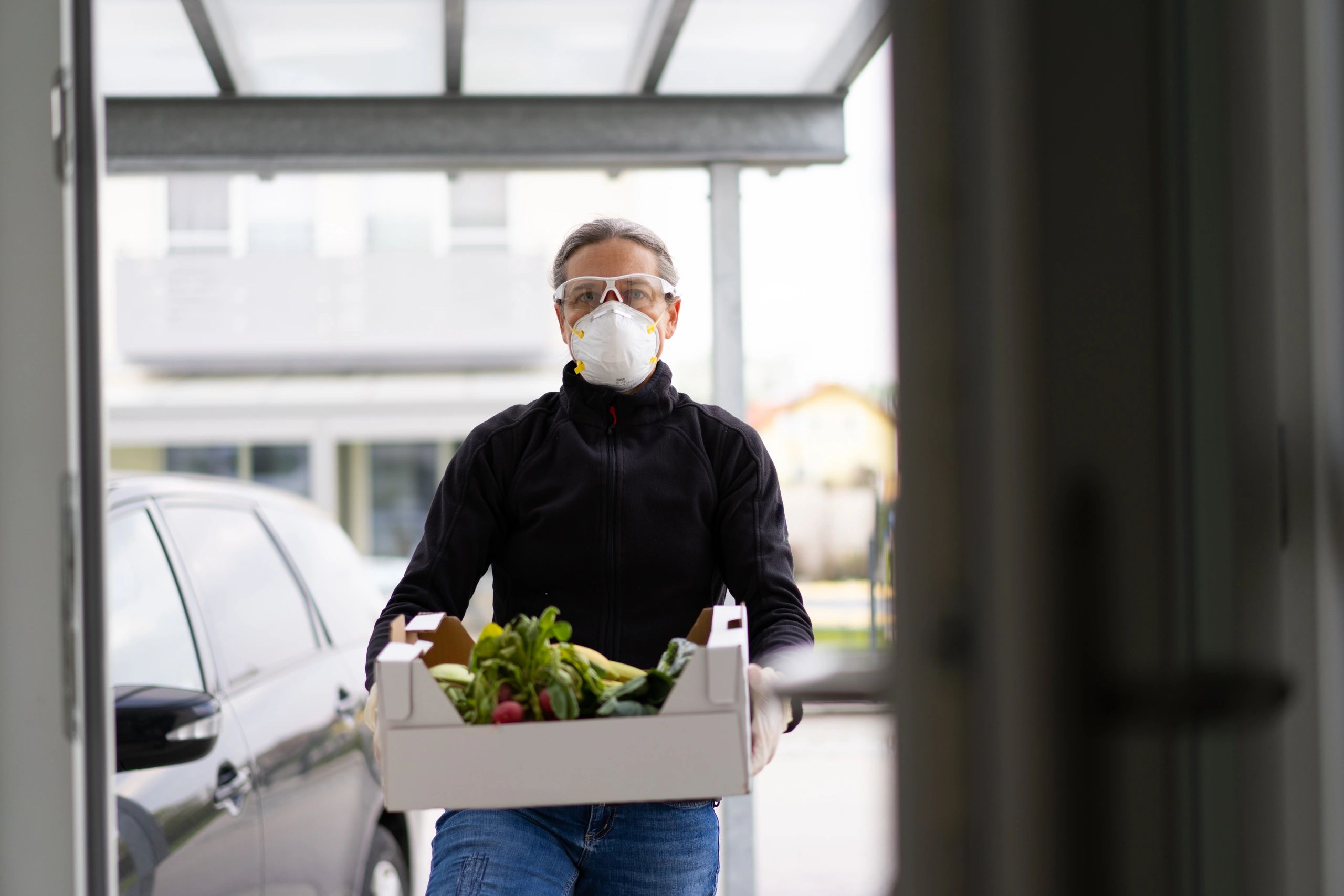 Delivery person holding a box of fresh food at a doorstep