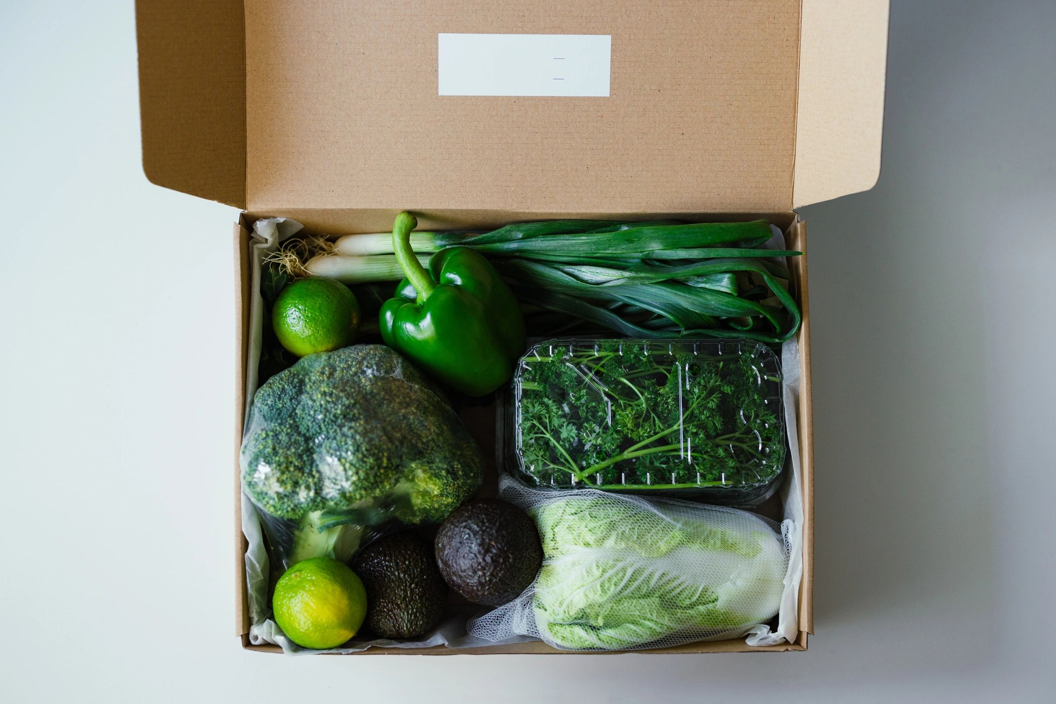 Box of fresh vegetables and fruits on a kitchen counter