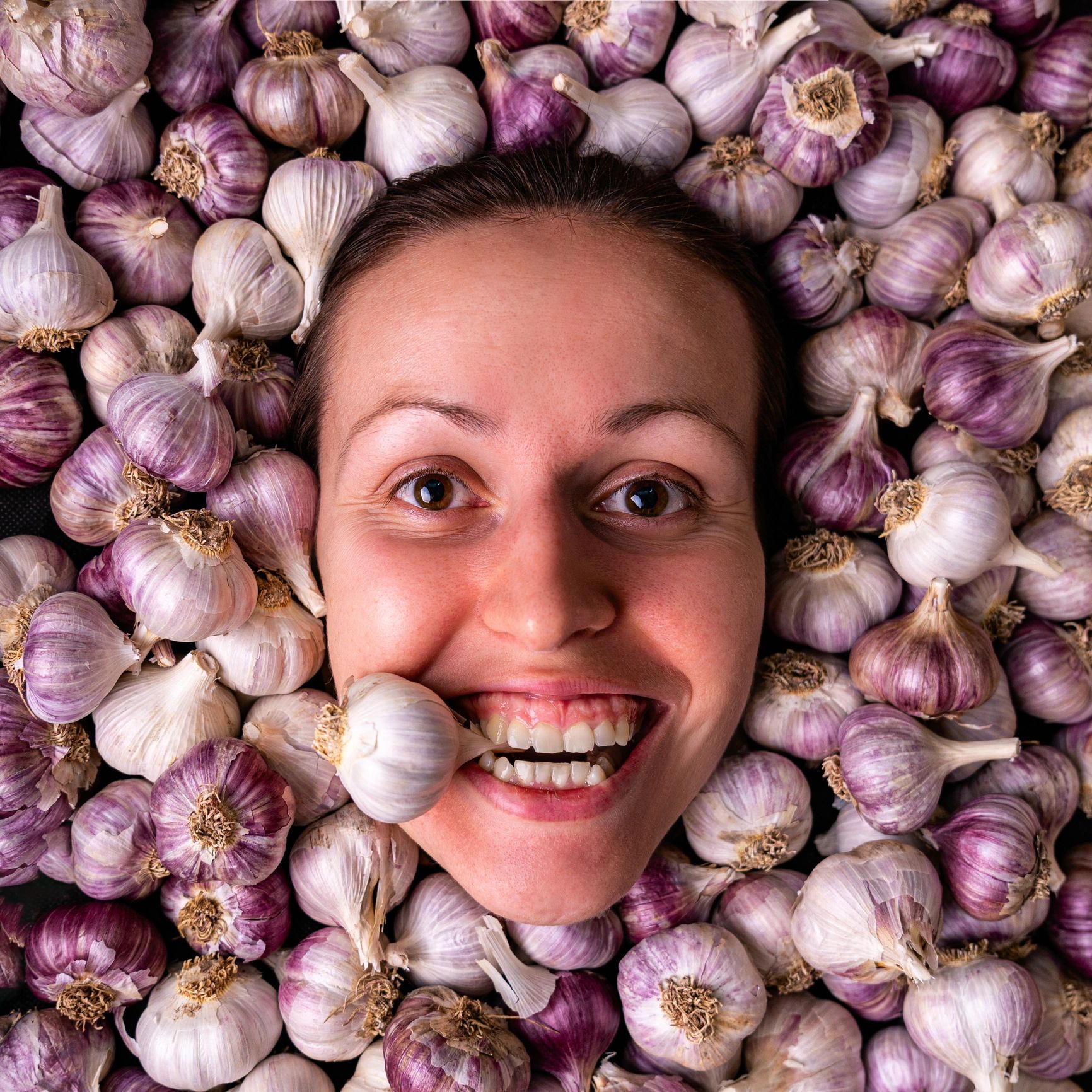 Portrait of a person among garlic bulbs