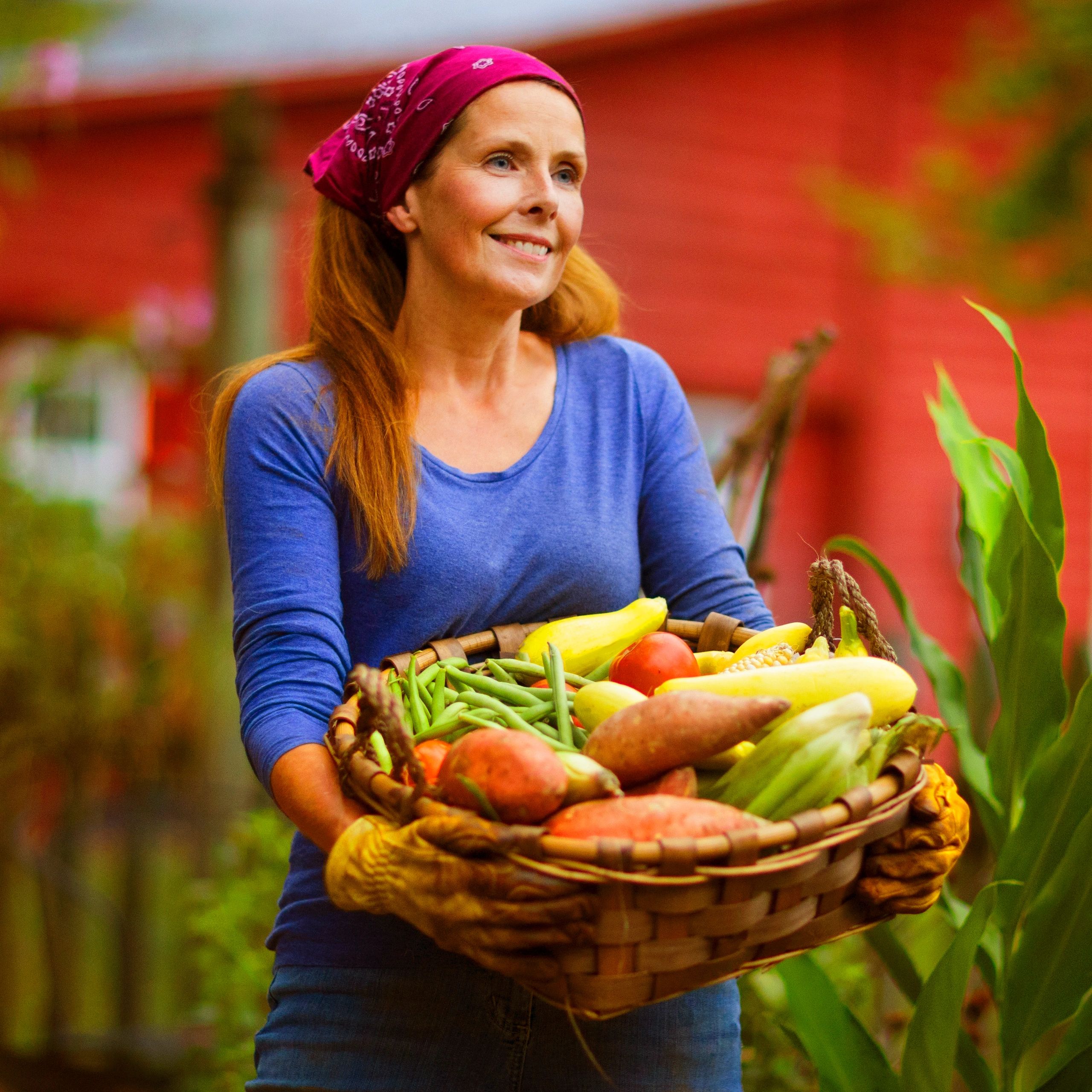 Team member standing by a table of garden vegetables